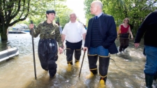 NDP Leader Jack Layton, right, takes a walk along a street immersed in flood waters alongside St-Paul fire chief Gilles Bastien, centre, and Major Marieeve Begin in the town of St-Paul-de-I'lle-aux-Noix, Que., Monday, May 30, 2011. (Graham Hughes / THE CANADIAN PRESS)